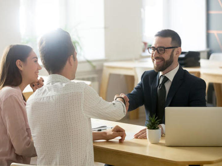 people at a desk shaking hands and smiling