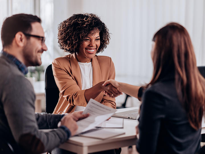 People at a desk, shaking hands.